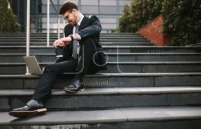 Businessman sitting on steps laptop and coffee