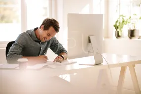 Entrepreneur making notes while working on computer at home